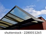 Small photo of strut, suspended glass roof above the building entrance. bus station, railway station. cable wind braces. aluminum construction with windows above pergola galvanized steel frame, brick wall, brown