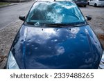 Small photo of hail damage to car. damaged hood and windshield