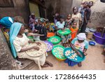 Small photo of Zinder, Niger - September 2013: Beautiful African girls in colorful clothes and turban making traditional sweet cookies from forgo flour in small kitchen local manufacture