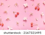 Pattern with jasmine flowers and sweet cherry on pastel pink background, lay flat, the top view.