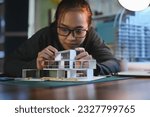 Small photo of Architecture students diligently make house model building samples with paper architecture and tools at night in their alone room.