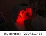 Woman having Ultraviolet LED light facial treatment at beauty salon. Cosmetology. female Face At Red Light Treatment At Beauty Clinic.