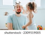Small photo of A father and daughter enjoying a funny and creative makeup session at home, with the dad encouraging his child's imagination. Laughter and Lipstick A Funny Father Daughter Moment Captured Forever