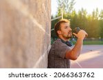 Small photo of Male athlete drinking or taking his dose of whey protein, bcaa, creatine, casein or energy drink, after a hard workout outside at sunset. Concept of wellness, nutrition, health care.