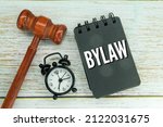 Small photo of an alarm clock, a hammer hammer and a notebook with the word bylaw