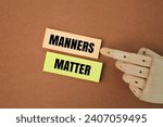 Small photo of wooden hand and colored paper with the word manners matter