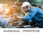 Small photo of Engineering worker man wearing uniform safety and hardhat working machine lathe metal in factory industrial, worker manufactory industry concept.