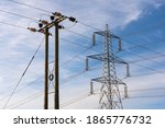 Examples of two overhead electricity pylons. Lattice steel pylon and a wooden pole pylon. Hertfordshire. UK