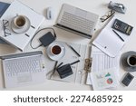 Small photo of Top view of a full business desk with laptops, accounting papers, calculator, coffee and other office supplies, success work or stress concept, high angle shot from above, selected focus