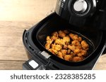 Small photo of homemade deep fried chicken are cooked by using a black air fryer or oil free fryer on wooden table in the kitchen for being a dinner during the christmas party with family members