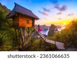 Happy and relaxed travel woman watching sunrise, tree house with diamond beach, Atuh beach in Nusa Penida island, Bali, Indonesia.