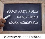Small photo of Woman hand pointing at chalkboard with the text yours faithfully yours truly and yours sincerely. Concept of complimentary closing of a formal letter.