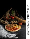Small photo of Italian Pizza Four Seasons (Pizza Quattro Stagioni) with different ingredients on the wooden table in the kitchen. Italian homemade recipes