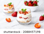 Berry dessert in glass with fresh strawberry, biscuit and whipped cream. Vegan lactose free dessert with alternative milk of coconut. Recipe of healthy organic dessert, cheesecake or berry trifle cake