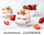 Italian strawberry tiramisu dessert with mascarpone and whipped cream, savoyardi crumb and fresh strawberry in glass on marble. Recipe of simple dessert, cheesecake, pudding or berry trifle cake.