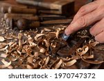 Small photo of CRAFTSMAN'S HAND CARVING WOOD WITH FIRMER GOUGE CHISEL AND WOODEN HAMMER MALLET IN THE WORKSHOP. HANDICRAFTS AND DIY CONCEPT.