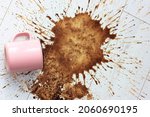 Small photo of A pink ceramic mug, cup fell on a white wooden parquet floor and left a big stain on it. Spilled coffee in the morning. Lots of hot coffee drink brown splashes flying in different directions flatly.