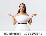 Small photo of Gorgeous smiling and creative asian woman create dress from pillow cinching with belt around waste raising hands up and grinning, showing her new outfit, standing white background