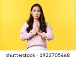 Small photo of Lifestyle, emotions and advertisement concept. Pitiful cute asian girl pouting and hold hands in plead, begging for favor or help, asking for something, feeling sorry, standing yellow background