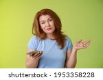 Small photo of Well meh. Indifferent careless hesitant redhead middle-aged woman mature red female shrugging hold smartphone smirk bored uninterested hold hand aside apathetic attitude green background