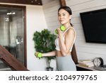 Active and healthy asian girl with fit body doing fitness exercises at home, lifting dumbbells and smiling, workout in living room