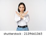 Image of young asian, korean girl student showing stop, cross prohibition sign, forbid smth, refusing, standing over white background