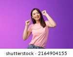 Small photo of Joyful glamour asian attractive girl having fun enjoy awesome party feeling carefree, fist pump during dance, smiling broadly like good music, attend concert, stand purple background