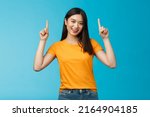 Small photo of Lively asian girl dark short haircut, tilt head cute smile camera, raise hands and pointing index fingers up, introduce top promo, grinning, bragging new cool purchase, stand blue background