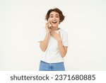 Small photo of Portrait of chatty young woman talking on mobile phone, laughing and smiling, answer telephone with surprised face, standing over white background.