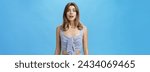 Small photo of Portrait of silly desperate and upset cute attractive woman with diastema open mouth gasping and frowning from worry and troublesome situation looking with begging eyes at camera over blue wall