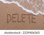 Small photo of Write the letters D E L E T E on the sand and there is sea water coming to erase the letters. Used to communicate the erasure disappears from the memory. or delete it or restart, message delete.