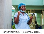 image of a black health professional wearing face mask under chin and stethoscope around neck,hands raised up for support and strength in covid-19 pandemic