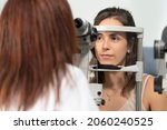 Small photo of Optometrist woman examining the eyesight of another woman with a slit lamp