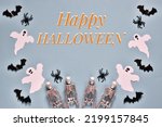 Happy Halloween greeting card. Flat lay composition with text Happy Halloween with the ghosts, spiders, skeletons and bats on light blue background. Postcard for holiday. Top view 
