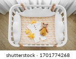 Small photo of Baby romper with toy bear for a newborn in cot, cradle. White wooden baby crib with pillows shaped clouds in baby's room. Top view of child's bed