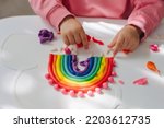 Child hands creating rainbow from play dough for modeling. Art Activity for Kids. Fine motor skills. Sensory play for toddlers.