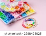 Small photo of Kids handmade beaded jewelry and different multi-colored beads for children's needlework and crafts in boxes. DIY art activity for kids. Motor skills, creativity and hobby.