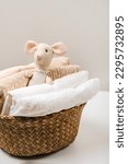 Small photo of Stack of baby clothes with cute little toy mouse in the basket. Cotton clothes and muslin swaddle blanket in pastel colors. Clean freshly laundered, neatly folded kids clothes.