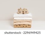 Small photo of Stack of baby clothes with baby shoes. Cotton clothes and muslin swaddle blanket in pastel colors. Clean freshly laundered, neatly folded kids clothes.