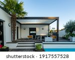 Trendy outdoor patio pergola shade structure, awning and patio roof, garden lounge, chairs, metal grill surrounded by landscaping