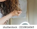 Woman scrunching her hair to form curls. Applying curly method for hair styling. Close-up on the hands