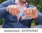 Close-up of a man's hands twisting a recyclable plastic bottle.