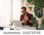 Small photo of Cheerful young businessman employee, HR manager having remote online work hybrid meeting or distance job interview, gesturing with hands during virtual video conference call in home office.