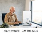 Focused older senior businessman typing on computer keyboard working in modern office. Busy male manager executive using computer analyzing digital tech data doing market research at workplace.