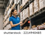 Young female worker in blue uniform checklist manage parcel box product in warehouse. Asian woman employee holding tablet working at store industry. Logistic import export concept.