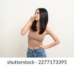 Small photo of Bad smell stinks. Young beautiful asian woman pinching nose with disgust. Holding breath with fingers on nose