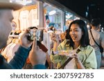 Asian woman enjoy eating noodles street food at night market. Traveler Asian blogger women Happy tourists Beautiful female with Traditional thailand bangkok food.