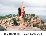 Small photo of Caucasian long-haired mature woman exercising on mountain summit barefoot and scantily clad