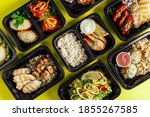 Small photo of Healthy lunch at the workplace. Pick up food in black containers with Cutlery on a yellow background