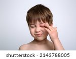 Small photo of Child with red swollen eye from insect bite. Quincke edema. Portrait of unhappy caucasian appearance boy. Isolated background. Face of allergic person. Copy space. Studio. Allergy. Sick body part.